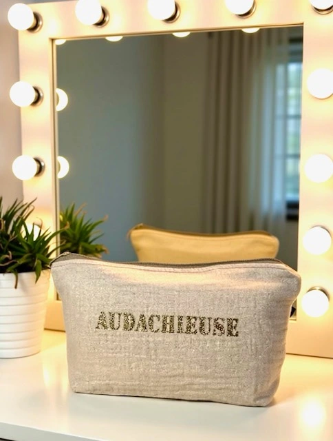Petite pochette en gaze de coton blanc crème scintillant avec son inscription "Audachieuse" en or pailleté. Fait main en série limitée.