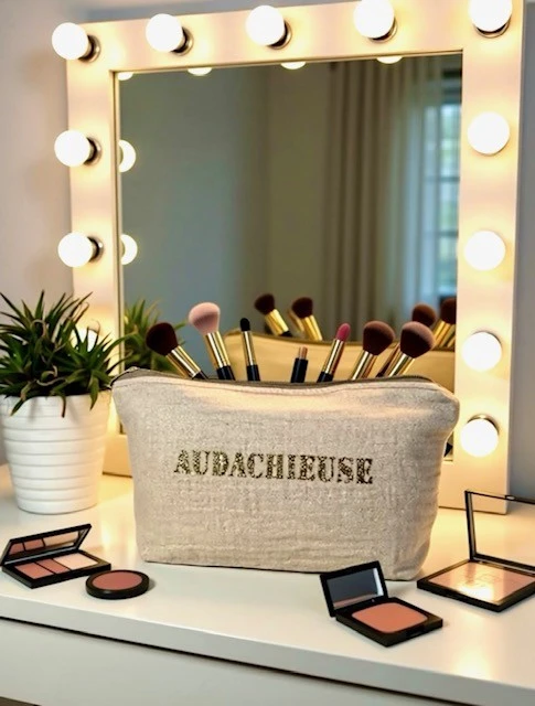 Petite pochette en gaze de coton blanc crème scintillant avec son inscription "Audachieuse" en or pailleté. Fait main en série limitée.
