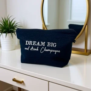 Trousse de toilette fait main en gaze de coton noir scintillant avec son inscription "Dream big and drink champagne" en argent pailleté.