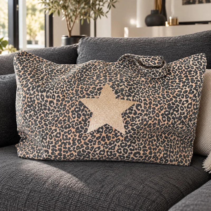 Très grand sac cabas léopard à étoile champagne pailletée posé sur un canapé gris anthracite dans un salon lumineux