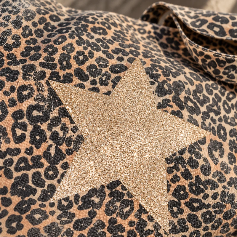 Gros plan sur la grande étoile champagne pailletée qui scintille sur l'imprimé léopard du maxi tote bag