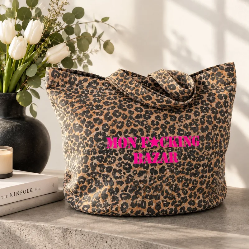 Tote bag léopard Mon F*cking Bazar slogan rose fluo posé sur une console